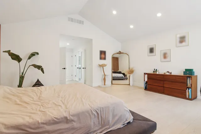 a bedroom with a bed large mirror and lamp