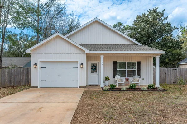 a view of a house with a yard plants and large tree