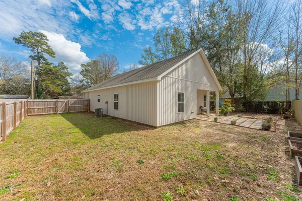 a view of a white house next to a yard with a large tree