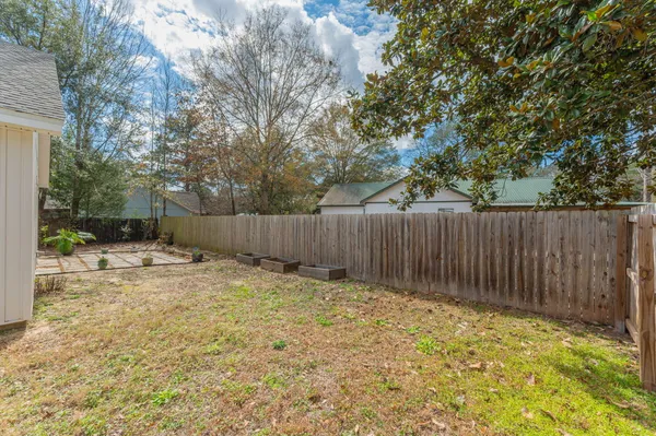 a view of a backyard with large trees and wooden fence
