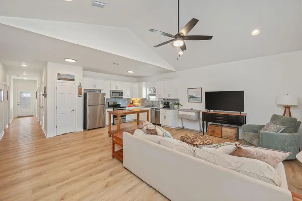 a living room with furniture kitchen view and a flat screen tv