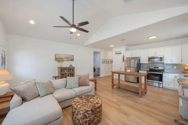 a living room with furniture kitchen view and a wooden floor