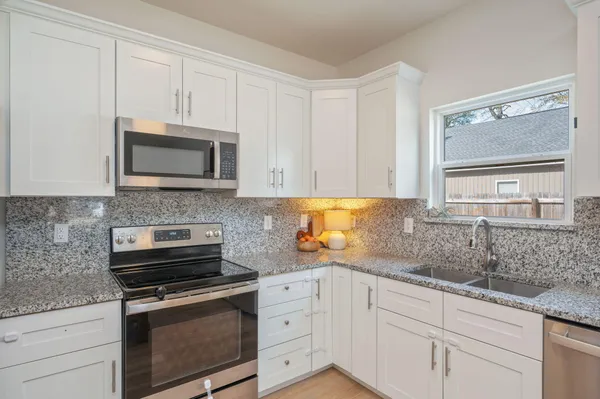 a kitchen with granite countertop white cabinets and stainless steel appliances