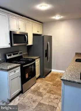 a kitchen with stainless steel appliances granite countertop a stove a sink and a microwave