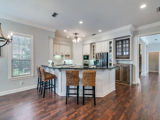 a kitchen with stainless steel appliances granite countertop a stove a sink a refrigerator dining table and chairs