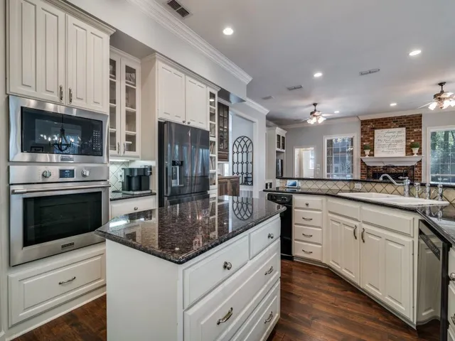 a kitchen with stainless steel appliances granite countertop a stove top oven a sink and a refrigerator