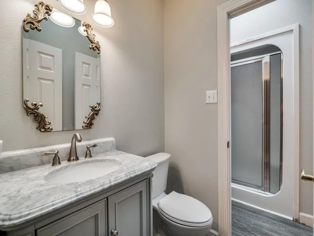 a bathroom with a granite countertop sink a toilet and a mirror