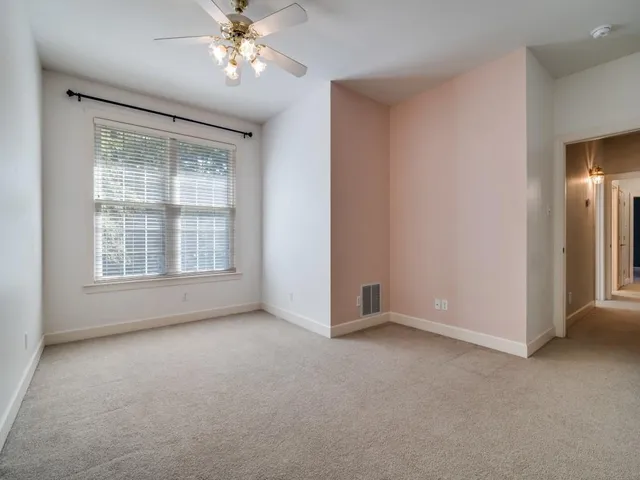 an empty room with chandelier fan and windows