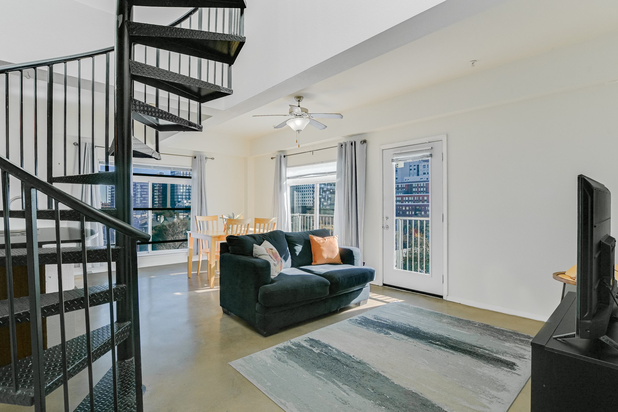 910 West 25th Street, Unit 607 Austin, TX 78705 - Photo 14 of 19 Living room featuring stairway, finished concrete flooring, and ceiling fan
