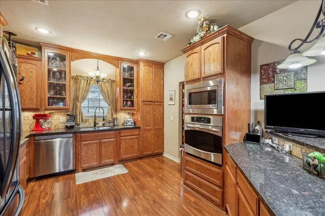a kitchen with stainless steel appliances wooden floors and wooden cabinets