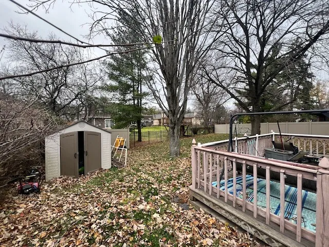 a view of a house with large wooden fence and large trees