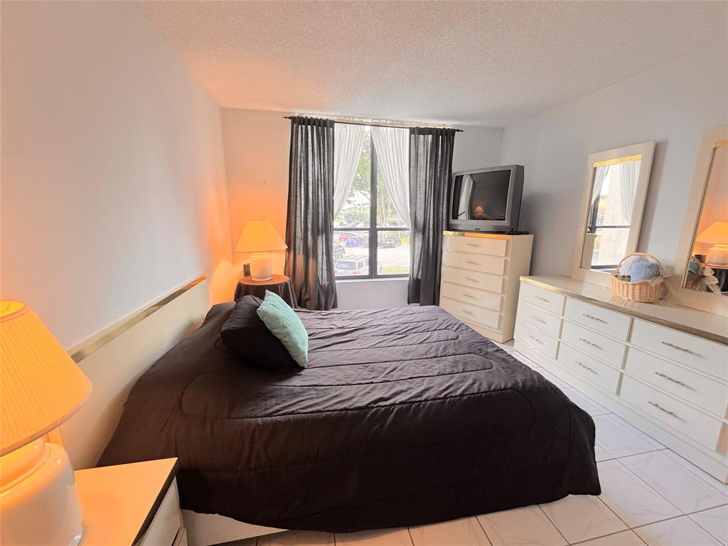 7950 West McNab Road, Unit 203 Tamarac, FL 33321 - Photo 14 of 21 a bedroom with a bed and a large mirror on the dresser