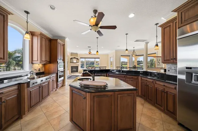 a large kitchen with granite countertop a stove a sink a dining table and chairs