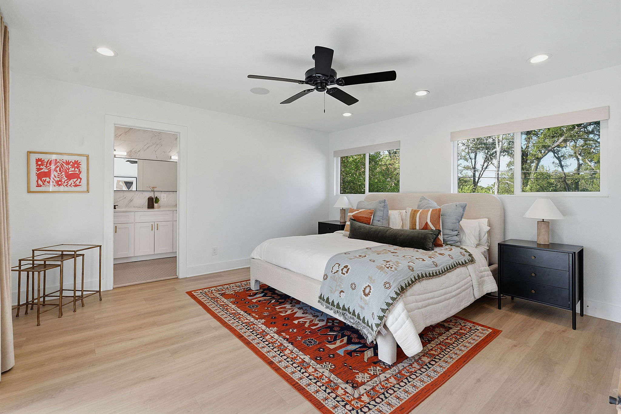 4403 Elmsgrove Drive Austin, TX 78721 - Photo 31 of 38 A well-lit primary bedroom offers ample space with light wood flooring and a view of verdant trees from its multiple windows.