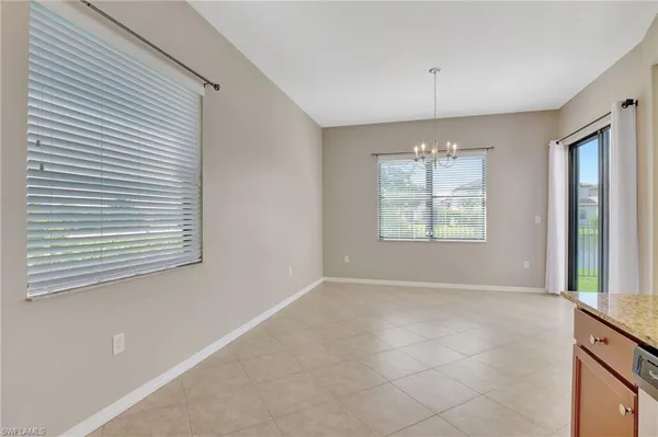 an empty room with windows and chandelier fan