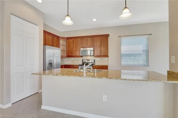 a kitchen with stainless steel appliances granite countertop a sink a refrigerator and a granite counter tops