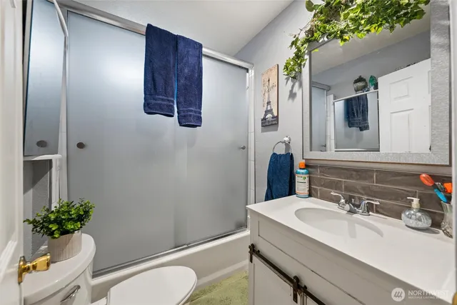 a bathroom with a granite countertop sink vanity mirror and toilet