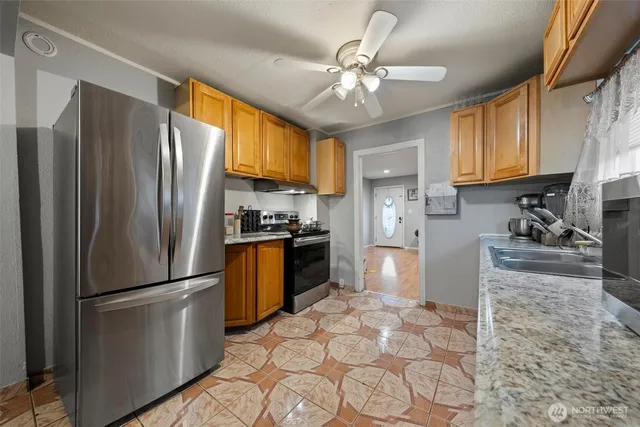a kitchen with granite countertop a refrigerator stove top oven a sink and dishwasher