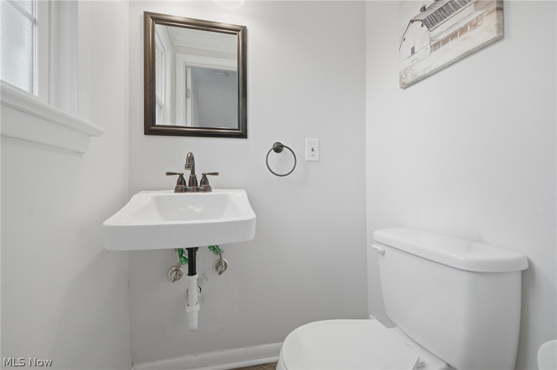3722 Lindholm Road Shaker Heights, OH 44120 - Photo 28 of 34 This bathroom features a wall-mounted sink with a bronze faucet and a framed mirror, complemented by a white toilet