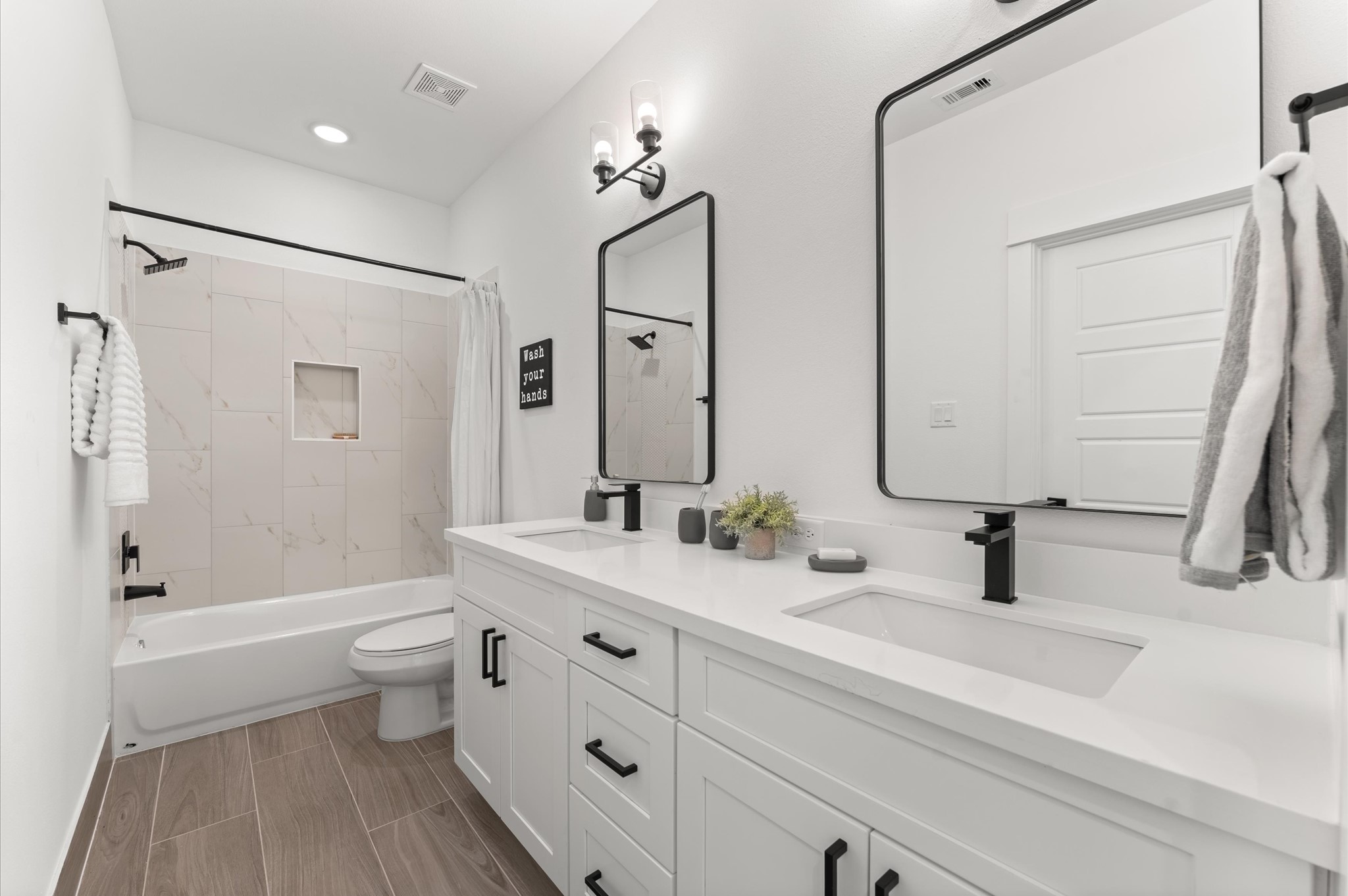 2710 Jensen Drive Houston, TX 77026 - Photo 19 of 38 Beautifully appointed Jack and Jill bathroom nestled between two secondary bedrooms on the first floor, designed to balance style and functionality. Each bedroom enjoys private access to the shared space, which features a sleek tub-shower combo, perfect for both quick rinses and relaxing soaks. Contemporary tilework, dual vanities, and bright lighting add modern appeal, while thoughtful layout enhances privacy and ease of use.