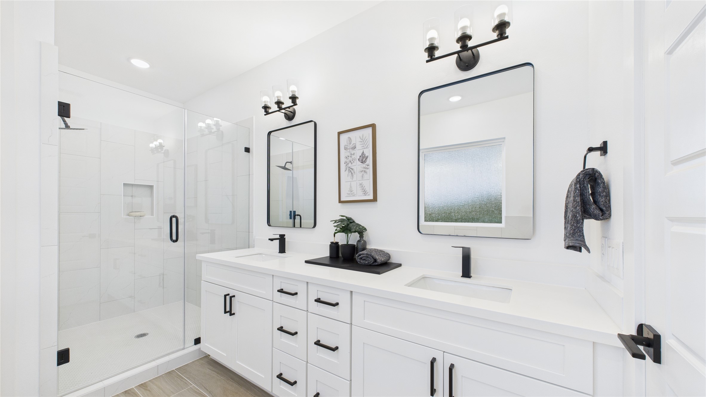2710 Jensen Drive Houston, TX 77026 - Photo 26 of 38 This stylish primary bathroom showcases a spacious walk-in shower framed with sleek glass panels and modern tilework that adds texture and sophistication. A double sink vanity anchors the space with clean lines and ample countertop room, complemented by an abundance of cabinetry that offers both function and flair. Contemporary finishes tie the room together, creating a polished retreat that balances luxury with everyday practicality.
