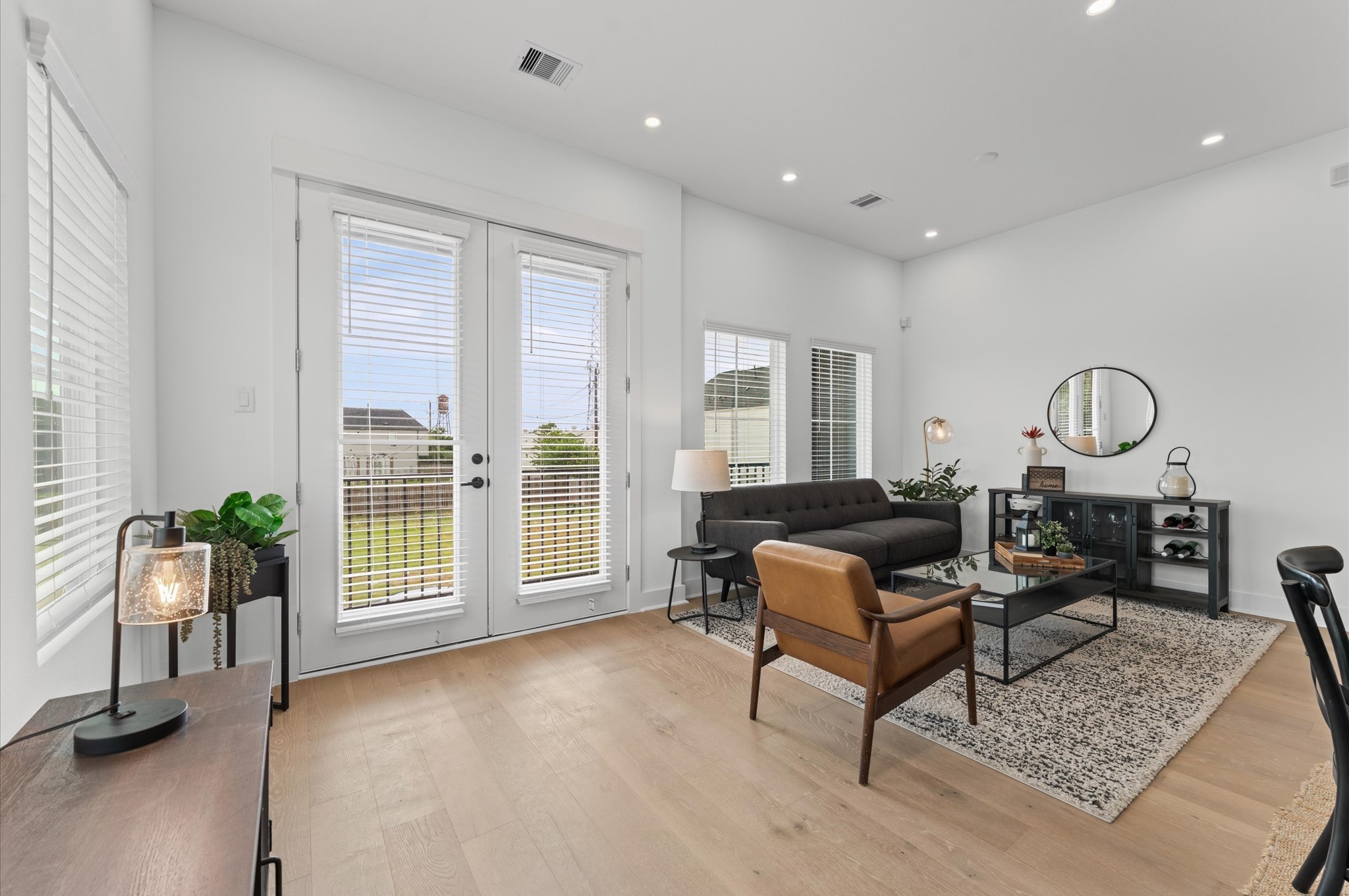 2710 Jensen Drive Houston, TX 77026 - Photo 8 of 38 Second-story open-concept living, dining, and kitchen area bathed in natural light, featuring elegant French doors that lead to a private balcony offering a glimpse of downtown. The seamless layout offers effortless flow for entertaining, complemented by modern finishes and skyline vistas that elevate everyday living.