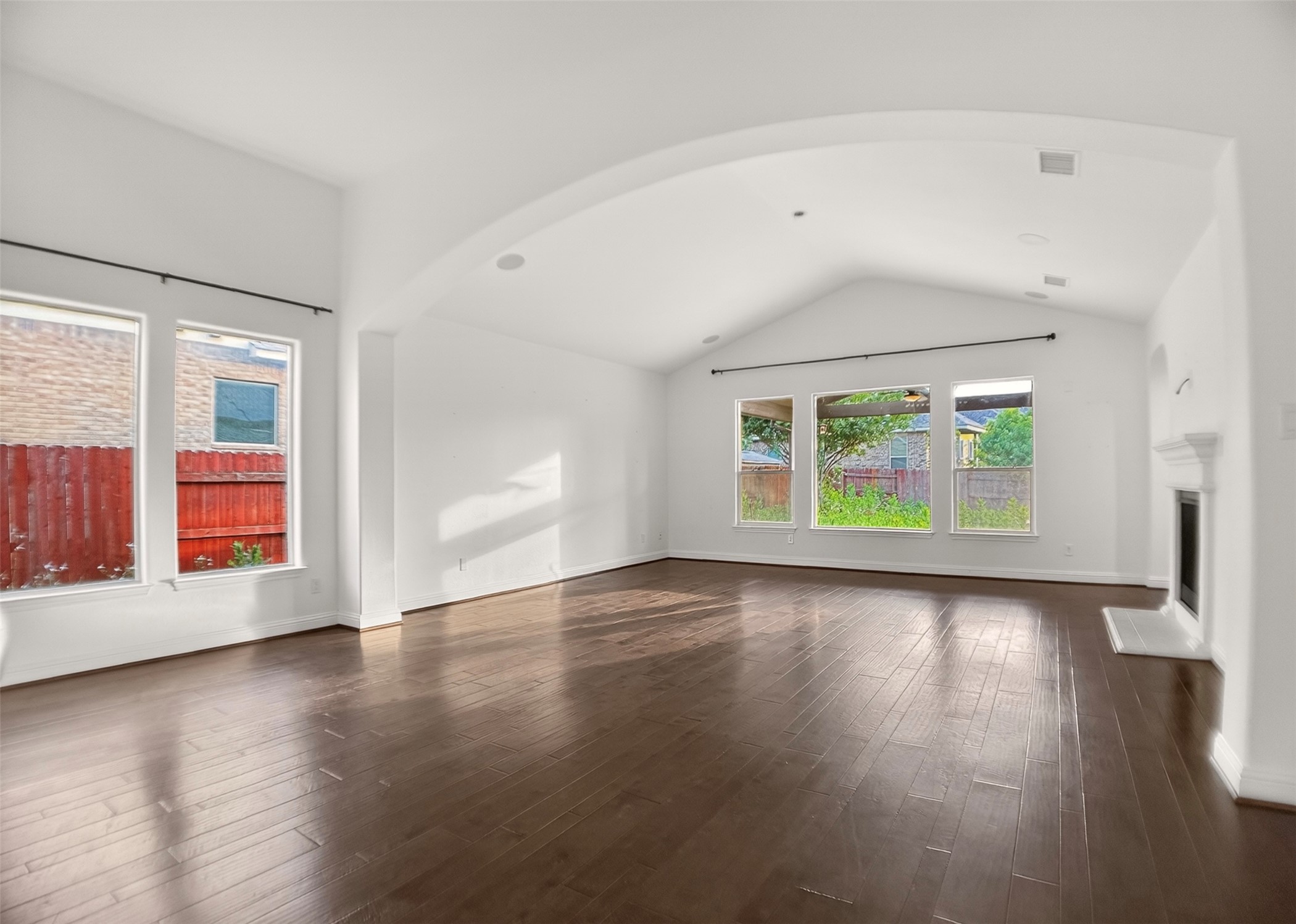 1505 Long Shadow Lane Georgetown, TX 78628 - Photo 10 of 28 Spacious living area featuring high vaulted ceilings, rich wood-finish flooring, multiple large windows, an elegant fireplace with a substantial mantel, and an arched architectural detail