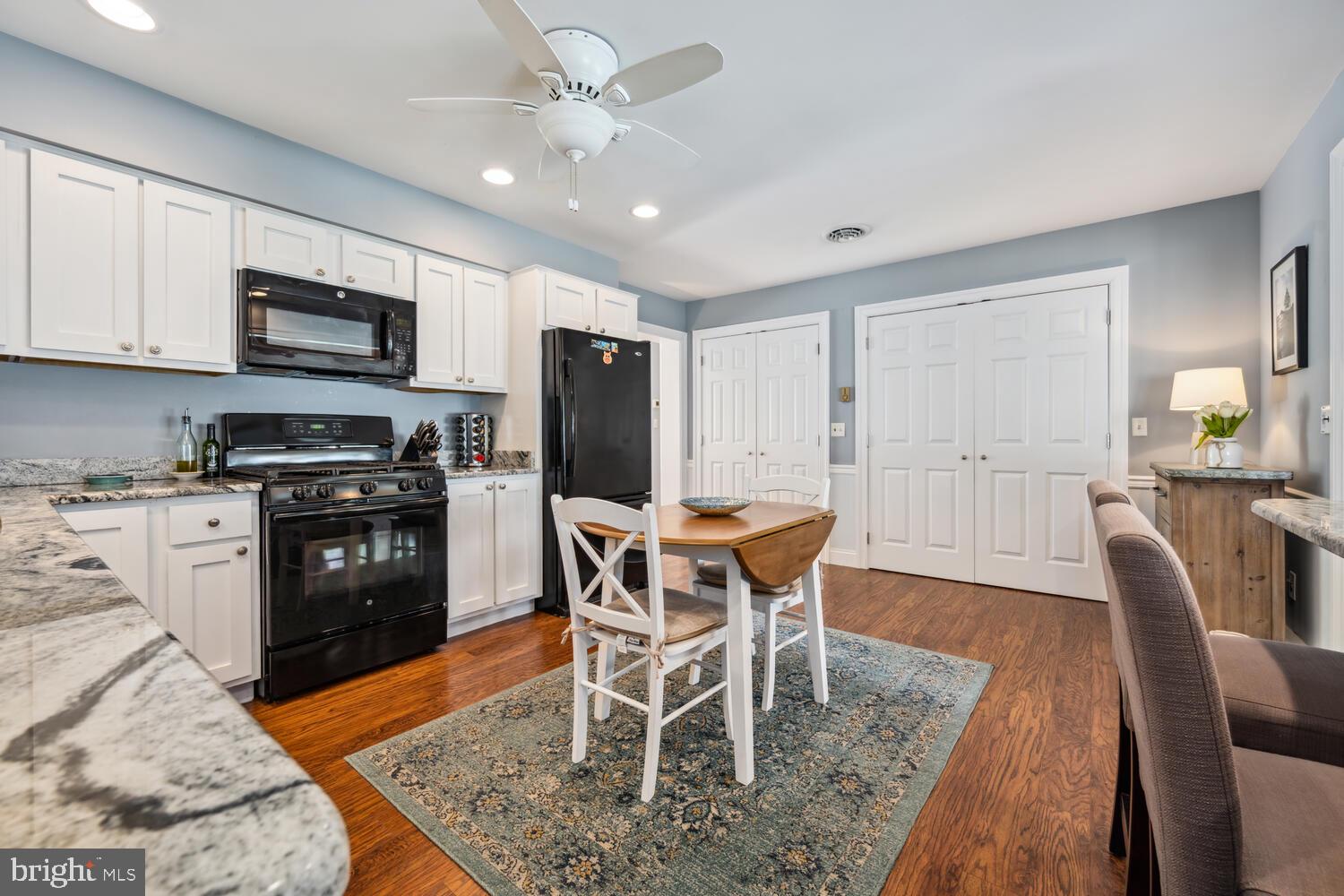 3 Oriole Drive Cambridge, MD 21613 - Photo 13 of 46 a kitchen with stainless steel appliances granite countertop a stove top oven a refrigerator a dining table and chairs with wooden floor