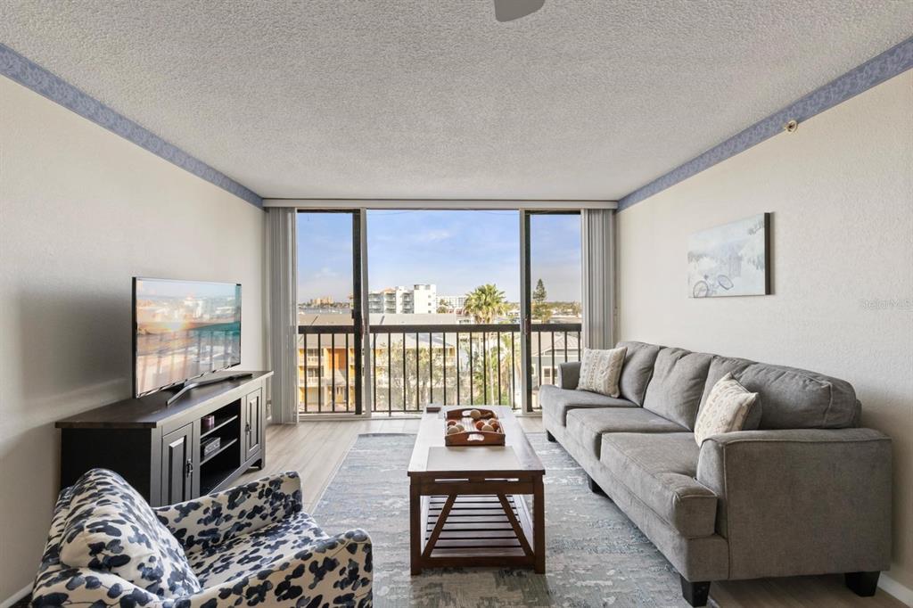 255 Dolphin Point, Unit 513 Clearwater Beach, FL 33767 - Photo 5 of 18 a living room with furniture and a flat screen tv