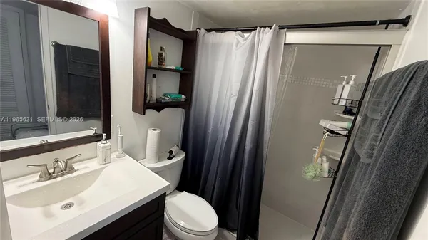 a bathroom with a sink a toilet a mirror and shower