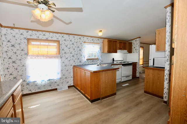 a kitchen with stainless steel appliances granite countertop a sink a stove a refrigerator cabinets and a dining table