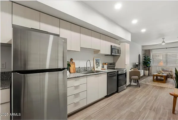 a kitchen with stainless steel appliances a refrigerator a stove a sink dishwasher a oven with white cabinets and wooden floor