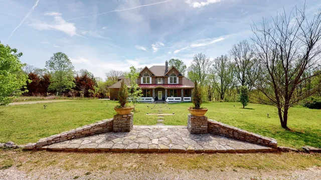 a front view of a house with a garden and a tree