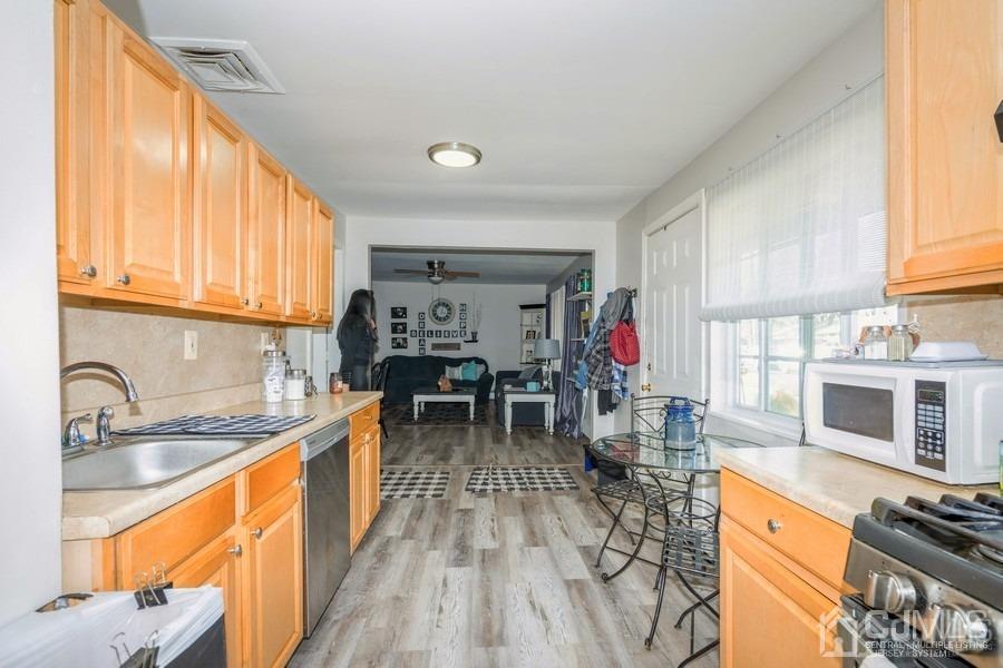121 Winthrop Road Edison, NJ 08817 - Photo 16 of 16 a kitchen with stainless steel appliances granite countertop a stove top oven a sink dishwasher a dining table and chairs with wooden floor