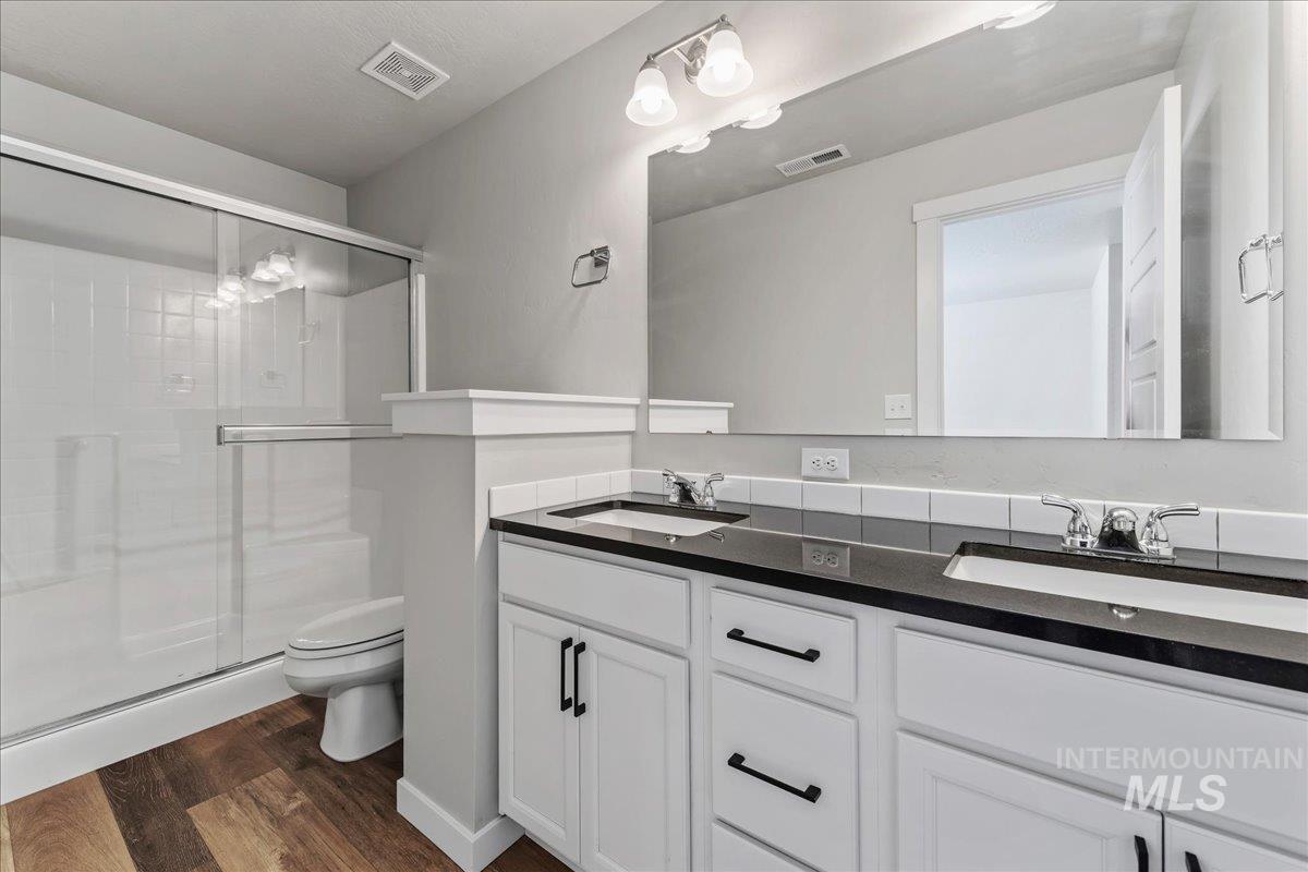 3091 S Green Boise, ID 83709 - Photo 18 of 27 Modern bathroom featuring a dual vanity with white cabinetry, dark countertops, and undermount sinks