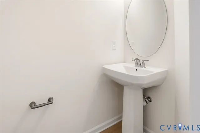 a view of a hallway with wooden floor and a bathroom