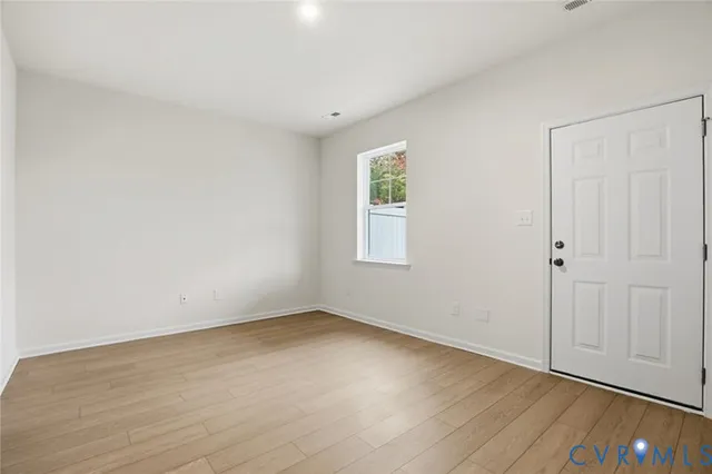 a view of an empty room with wooden floor and a window