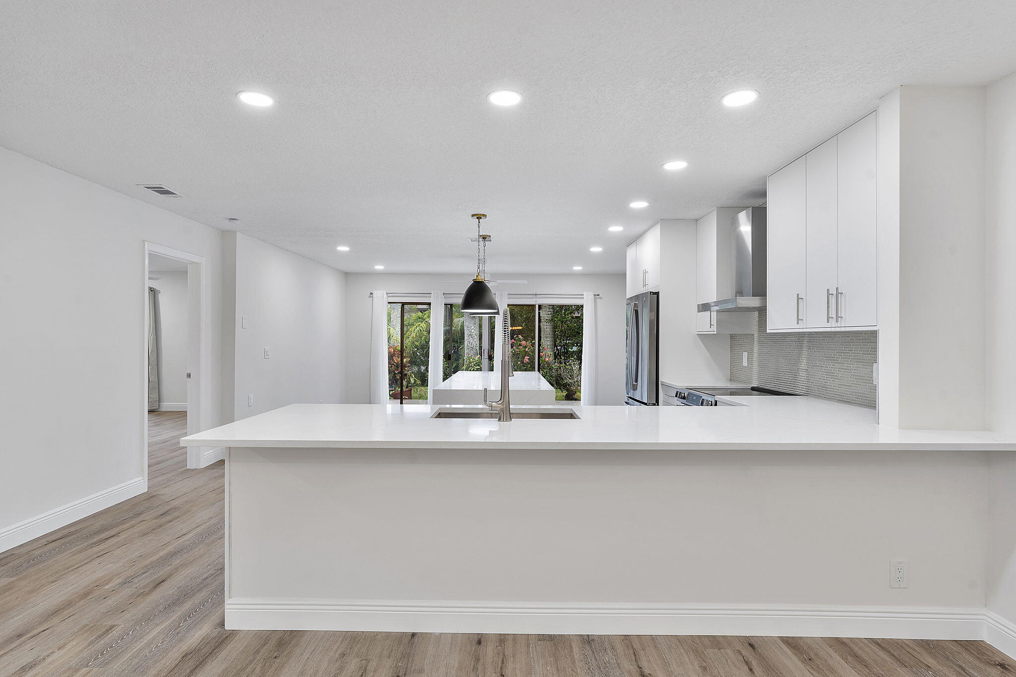 9180 Pine Springs Drive Boca Raton, FL 33428 - Photo 8 of 29 a large white kitchen with kitchen island a sink stainless steel appliances and cabinets
