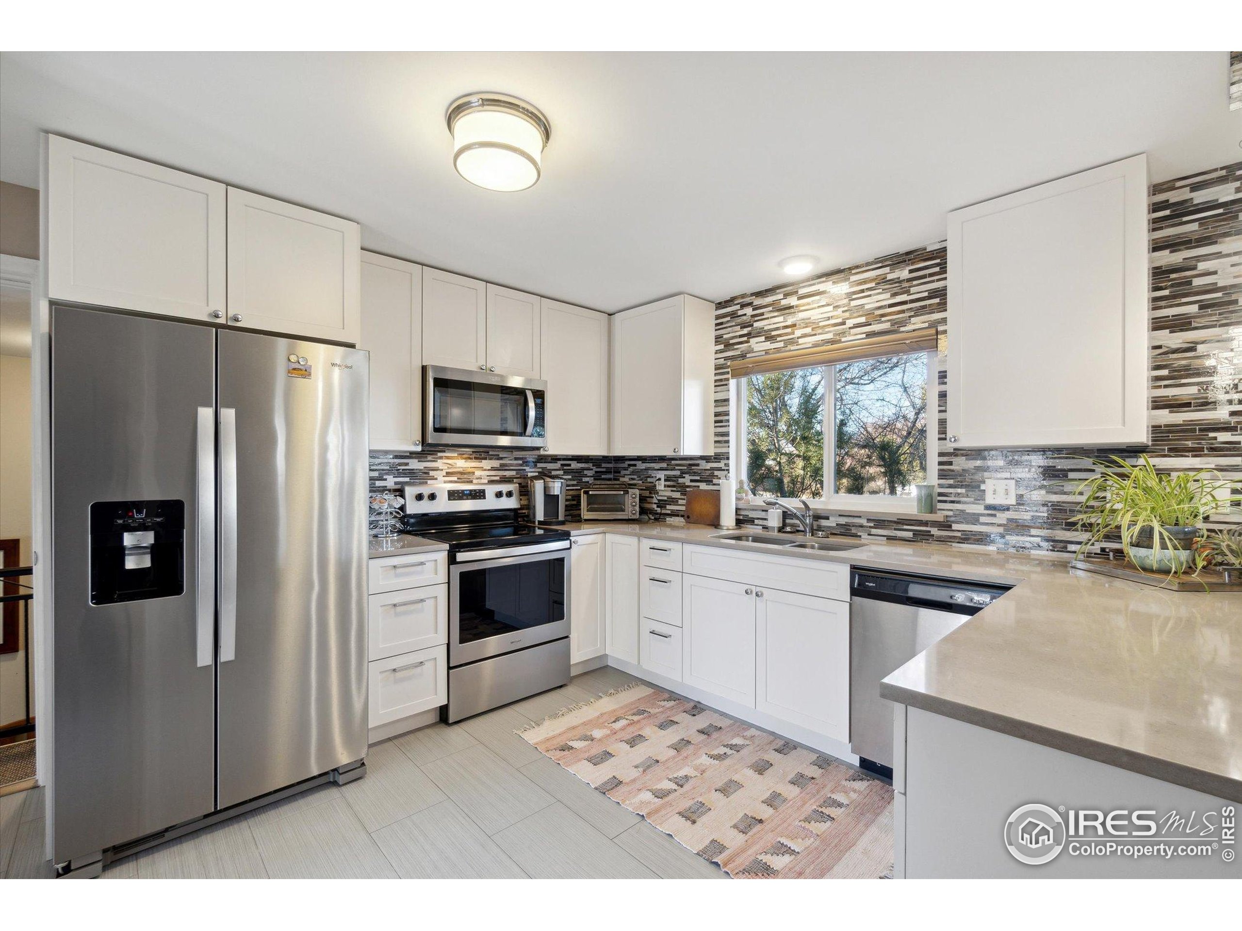 1034 Spring Drive Boulder, CO 80303 - Photo 13 of 49 a kitchen with granite countertop a refrigerator oven a sink dishwasher and white cabinets with wooden floor