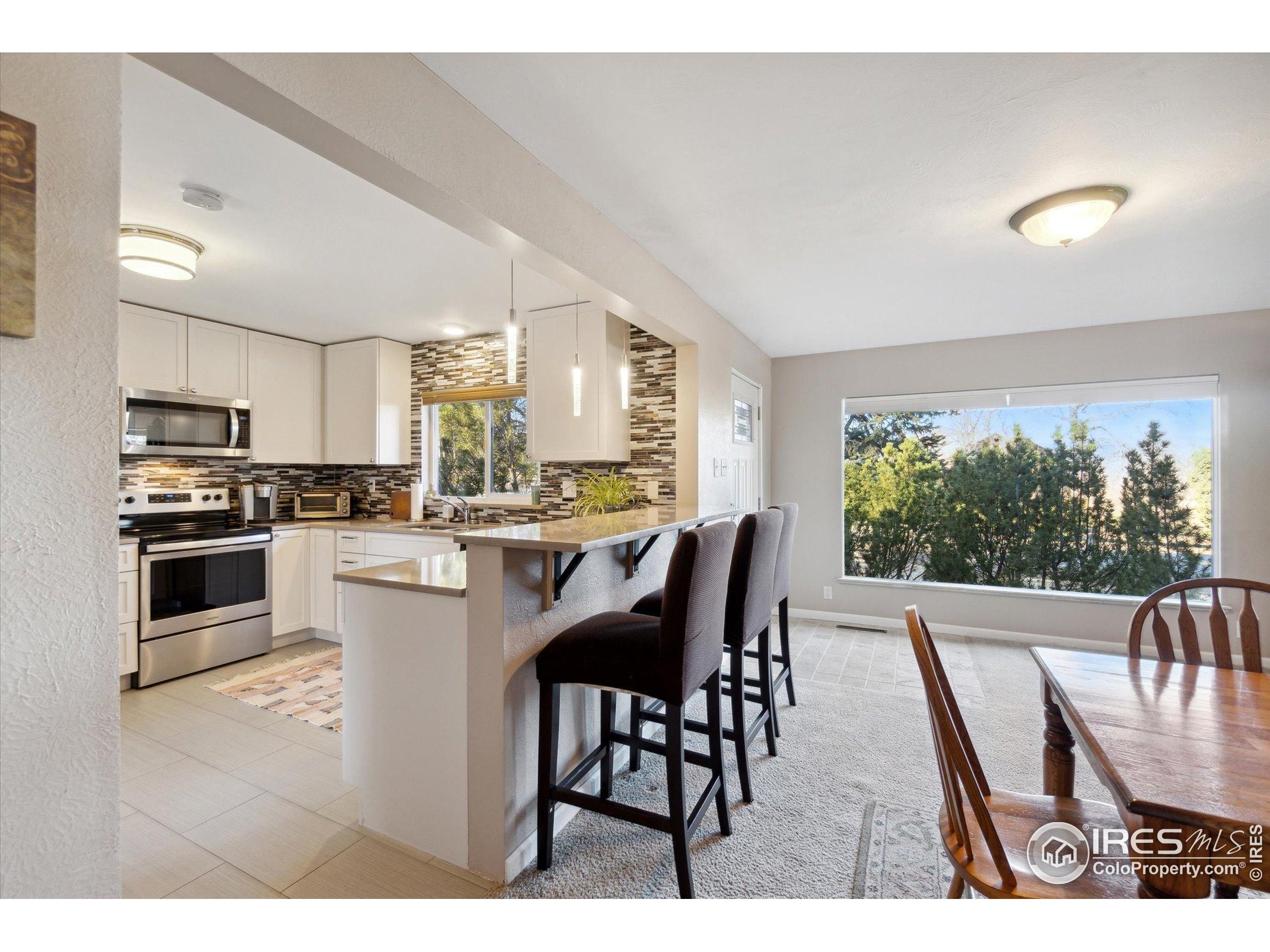 1034 Spring Drive Boulder, CO 80303 - Photo 16 of 49 a kitchen with stainless steel appliances granite countertop a stove a refrigerator a kitchen island a table and chairs