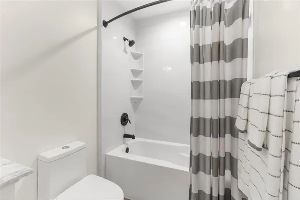 a white toilet sitting next to a bath tub and shower