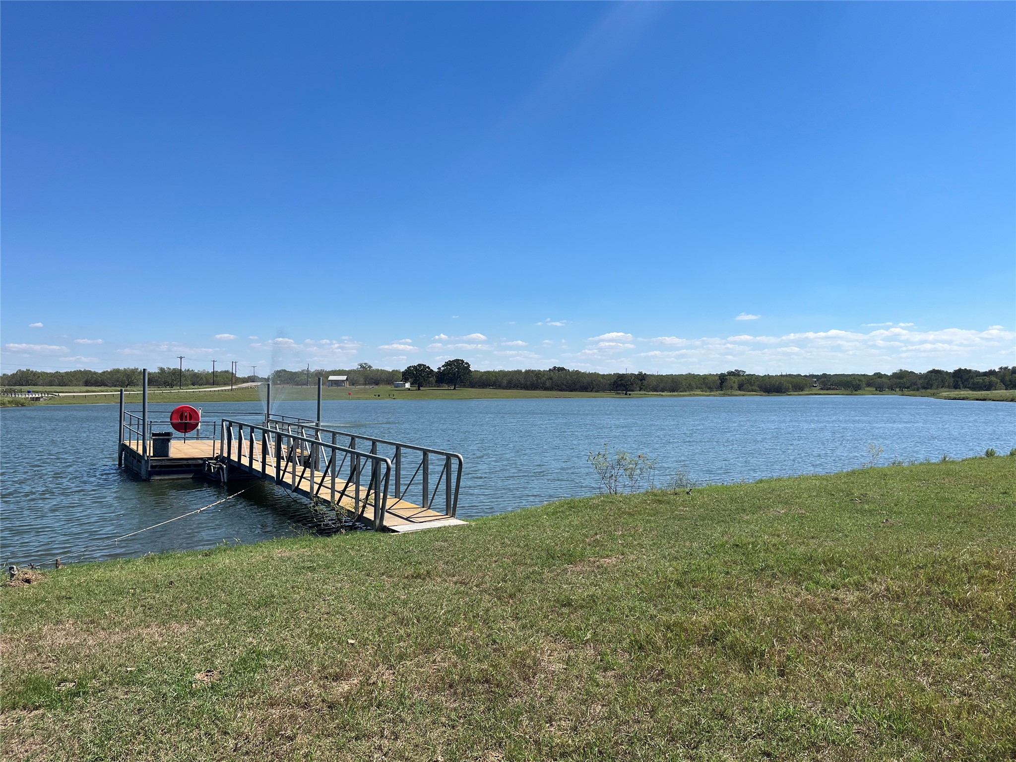 Tbd Flash Circle Luling, TX 78648 - Photo 8 of 9 A private wooden dock with metal railings extends into the calm water under clear blue skies.