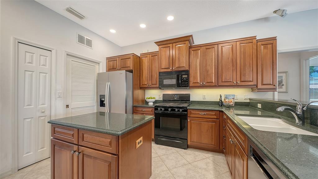 665 Crane Prairie Way Osprey, FL 34229 - Photo 17 of 61 a kitchen with stainless steel appliances granite countertop a sink stove refrigerator and cabinets