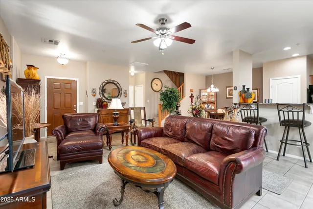 a living room with furniture a clock and a ceiling fan