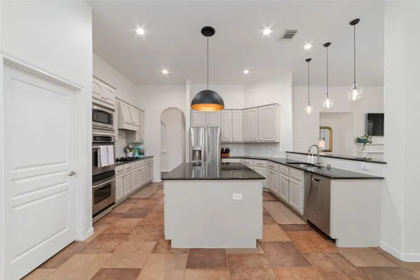 a kitchen with stainless steel appliances granite countertop a sink a stove a refrigerator and a dining table