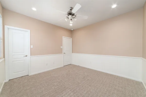 an empty room with a chandelier fan and windows