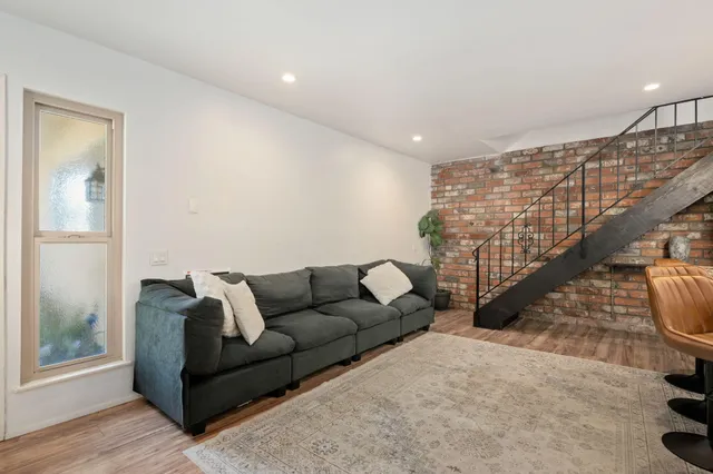 a living room with furniture stairs and a wooden floor