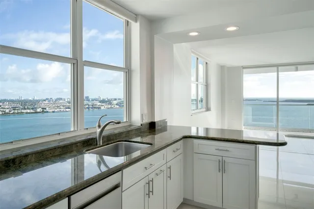 a kitchen with stainless steel appliances granite countertop white cabinets and a stove
