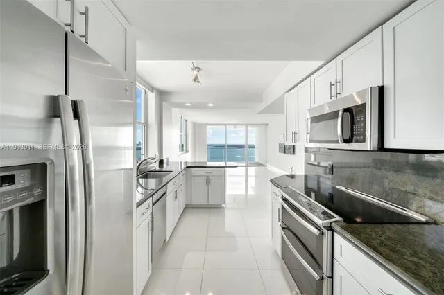 a kitchen with stainless steel appliances granite countertop a sink and a refrigerator