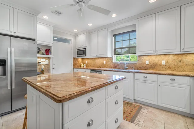 a kitchen with granite countertop a sink a center island and stainless steel appliances